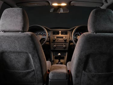 Cluttered and basic factory car interior with plain grey fabric seats and basic radio dashboard under flat lighting