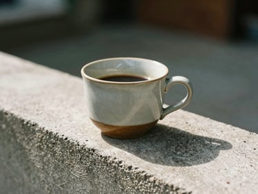 A ceramic coffee cup resting on a textured concrete ledge, soft natural daylight, shallow depth of field.