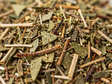 A detailed macro shot of the textured yerba mate cut, showing green leaf flecks, toasted twigs, and minimal dust under soft, natural light.