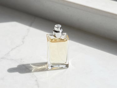 A single heavy glass perfume bottle casting a long, crisp shadow on white marble, warm morning light