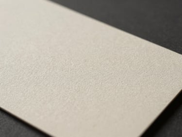 Extreme close-up of a heavy debossed business card on uncoated linen paper, casting a soft shadow under natural side-light.