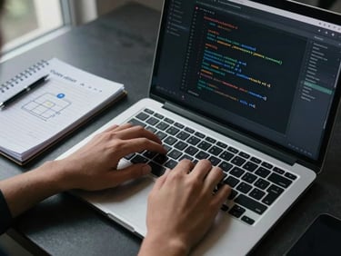 Close-up overhead shot of hands typing on a laptop keyboard at a standing desk, a terminal window open with infrastructure-as-code visible on screen, cool daylight from a window to the left, a spiral notebook with handwritten provider architecture notes beside the laptop, high contrast, no faces visible