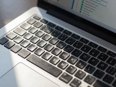 Tight overhead crop of a laptop keyboard with a Terraform plan output visible on screen, cool daylight from the left casting sharp shadows across the keys, high contrast