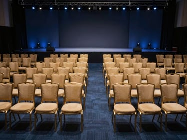 Rows of premium VIP chairs neatly arranged in front of a corporate stage, clean symmetry, professional event setup