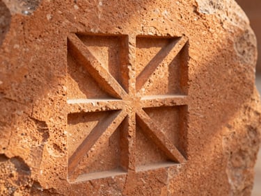 Close-up of a chisel carving geometric patterns into warm orange tufa stone, dust particles in sunbeam