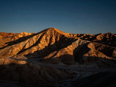 Expansive desert mesa with dramatic rock formations under a deep twilight sky, high contrast, 35mm
