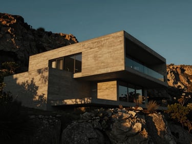 Cinematic low-key shot of a modern architectural concrete villa nestled in cliffs at golden hour, deep dramatic shadows, 35mm photography