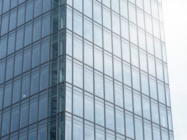 Modern glass skyscraper reflecting bright diffused daylight, clean architectural lines, cool blue tones