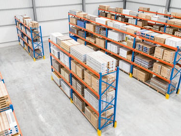 High-angle architectural view of an organized warehouse with clean high-key daylight, blue and orange rack structures