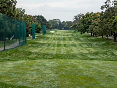 A bronze-tier community park golf course with clear safety nets and wide fairways, soft overcast daylight.