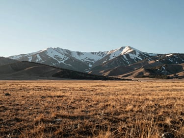 An expansive, quiet landscape of the Colorado Rocky Mountains under bright morning light, snow-dusted peaks, structured minimalist composition with generous negative space.