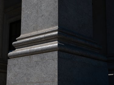 Architectural detail of a modern supreme court building stone pillar, sharp focus, dramatic dark shadows, silver highlights