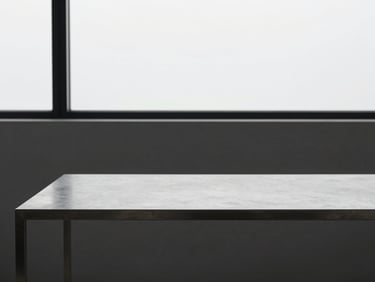 Minimalist modern workspace with a clean metal desk, cool architectural window light, desaturated tones, sharp focus, 35mm