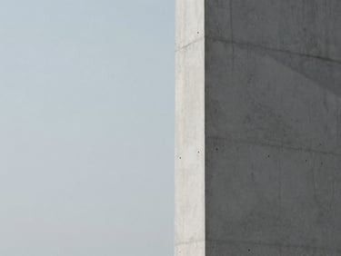Minimalist architectural detail of a stark concrete column casting a sharp shadow, desaturated cool tones, overcast light.