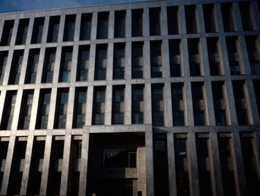 Cinematic wide shot of a modern monolithic government building facade at dusk, high-contrast chiaroscuro, 35mm