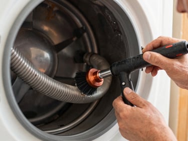 Close-up of a technician using a specialized brush and vacuum to clean a dryer vent hose, lint visible, natural indoor light, 35mm