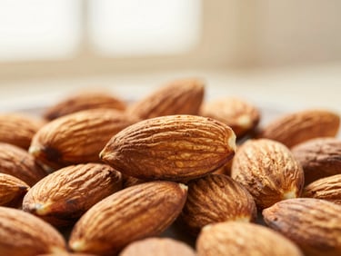 Close-up macro shot of stone-ground almonds, rich texture, warm diffused side-light, shallow depth of field, muted cream and terracotta tones.