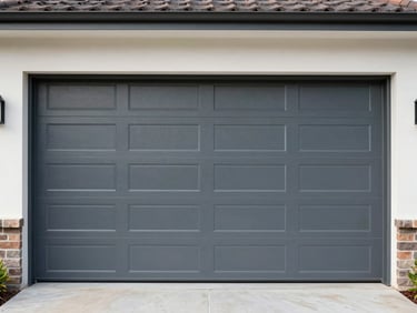 Close environmental shot of a freshly installed modern steel garage door on a residential home, overcast natural daylight, door panels showing crisp horizontal shadow lines, no people