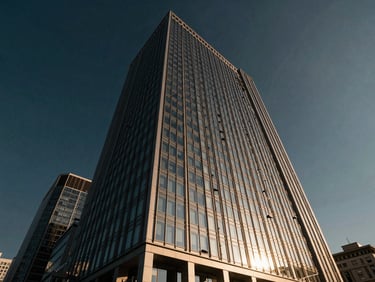 Dramatic low-angle architectural shot of a modern glass-and-steel corporate skyscraper in Istanbul's business district, reflecting deep navy sky and warm golden-hour light.
