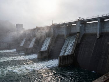 Hydroelectric dam wall with rushing water channels, misty morning light reflecting off dark wet concrete
