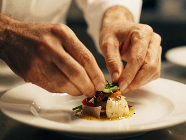 Close-up of a chef's hands delicately garnishing a dish in a warm, soft-lit kitchen, shallow depth of field, rich tactile textures, 35mm film aesthetic.