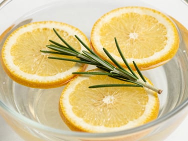 Crisp macro shot of fresh rosemary and citrus slices floating in clear water, bright daylight, 35mm lens