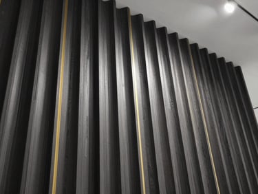 Low-angle architectural crop of a fluted wood-composite wall panel installation under dramatic gallery lighting