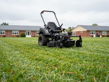 Low-angle action shot of a professional commercial ride-on mower cutting a wide school lawn, clean straight lines in the turf, bright overcast British daylight, crisp details of the machinery.