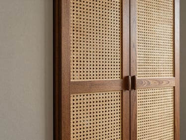 Detail shot of a wardrobe door with natural cane weaving set into a dark walnut frame, soft daylight catching the rich tactile texture.