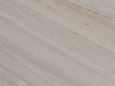 Extreme close-up of a natural quartzite slab with subtle warm veins, honed matte finish