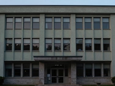 An institutional building facade at dusk, quiet architectural environmental shot, muted cool tones, 35mm lens.