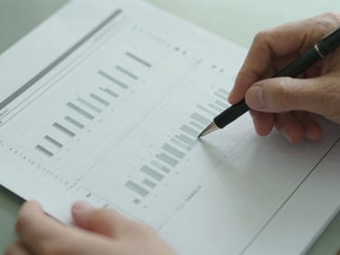 Close-up of hands reviewing a printed data report with charts, natural diffused daylight, muted cool tones, 35mm lens