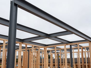 Wide environmental shot of a modern timber framing site, overcast daylight, steel beams and raw wood, sharp focus, 35mm lens