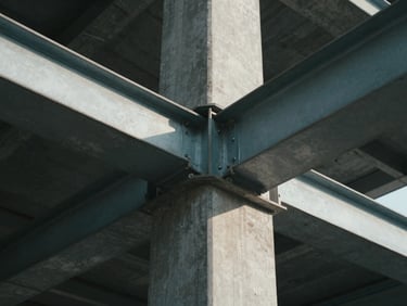 Symmetrical low-angle architectural framing of steel and concrete joints, sharp directional light, deep shadows, cool daylight.