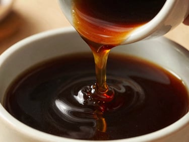 Slow pour of viscous dark molasses from a ceramic vessel, rich amber highlights, shallow depth of field