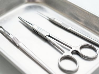 Macro shot of sterile surgical forceps and clamps on a clean metal tray, bright clinical lighting