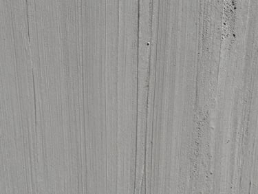 Extreme close-up of board-formed concrete, showing the exact imprint of wood grain in the gray surface.