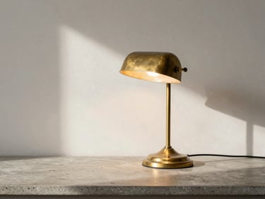 A mid-century solid brass desk lamp on a concrete countertop, warm natural light casting soft shadows, showing authentic patina, 35mm lens