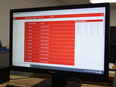 Vista de pantalla de control de inventario en NUBEFACT, mostrando stock en tiempo real con alertas rojas de nivel bajo y códigos de barras generados en dólares USD.