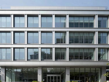 Straight-on architectural shot of a modern commercial office exterior, glass and steel, bright daylight, 35mm