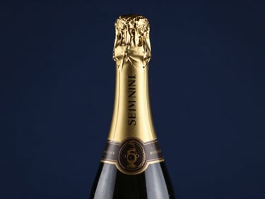 Macro shot of a premium champagne bottle neck with gold foil, elegant studio lighting, subtle reflections on glass, deep navy background, sharp focus, 50mm