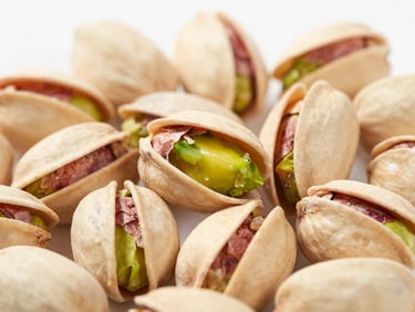 Macro close-up of natural whole pistachio kernels on a white clinical background, bright studio light, sharp focus.