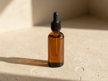 Warm editorial close-up of a single amber glass bottle of argan oil on a textured cream tadelakt surface, soft golden-hour light, shallow depth of field, 35mm