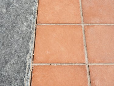 Macro texture shot of clean terracotta tiles contrasting with slate grey elements, sun-drenched industrial realism