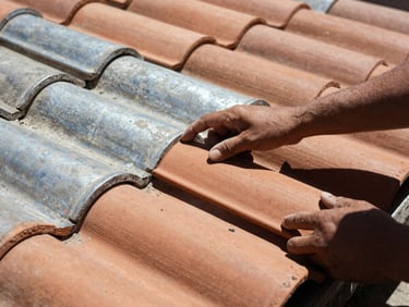 Close-up of hands inspecting terracotta roof tiles under harsh sunlight, high contrast shadows, 35mm