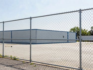 Crisp documentary photography of a newly installed galvanized chain-link fence around a commercial property in Westchester, bright morning daylight, natural colors, sharp focus, clean lines, 35mm lens