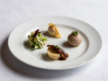 45-degree angle shot of a three-course wedding dinner plate, white porcelain, starter of dressed salad, clean studio lighting from above-left, crisp white tablecloth visible