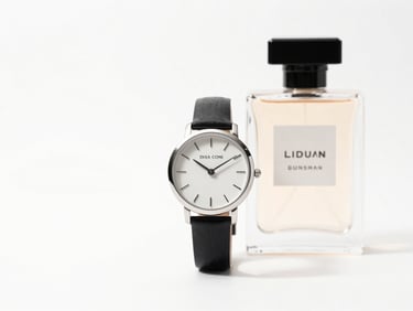 Elegant minimalist wristwatch next to a luxury perfume bottle, high contrast studio lighting