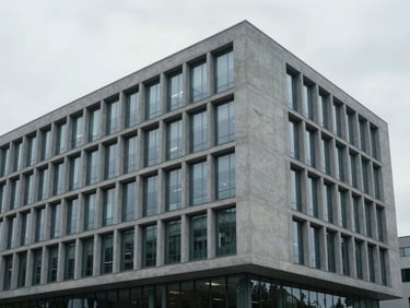 Minimalist architectural lines of a modern corporate headquarters, cool clinical gray concrete and glass facade, soft overcast daylight, clean composition.
