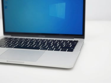 Eye-level macro shot of a clean refurbished business laptop open on a white workbench, cool blue screen, bright clean studio lighting, 35mm
